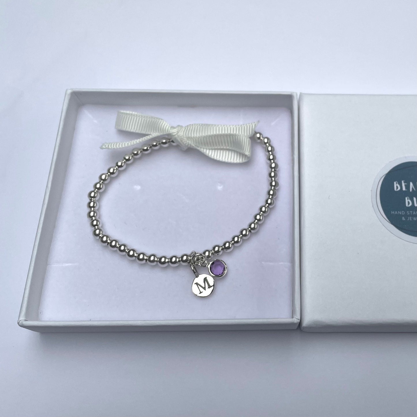 Silver-plated elasticated bead bracelet with silver initial & birthstone charm