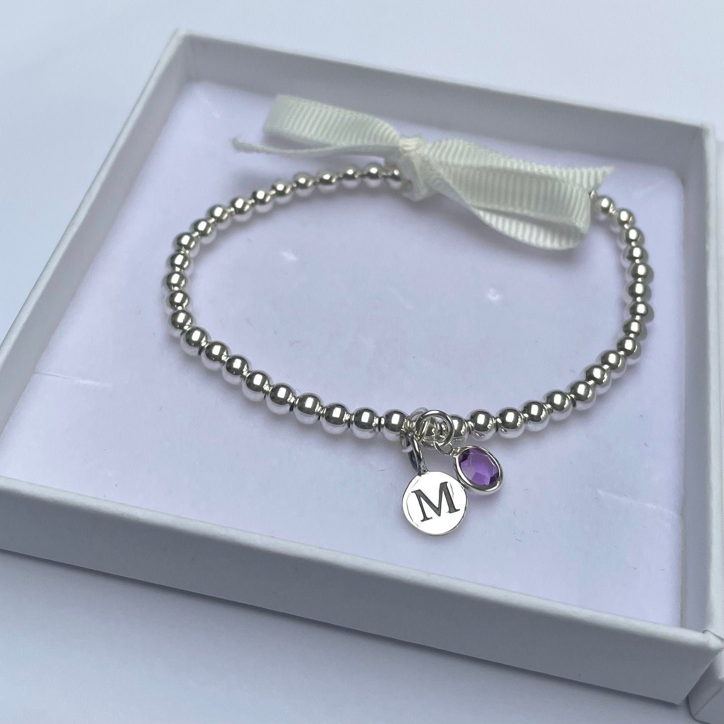 Silver-plated elasticated bead bracelet with silver initial & birthstone charm
