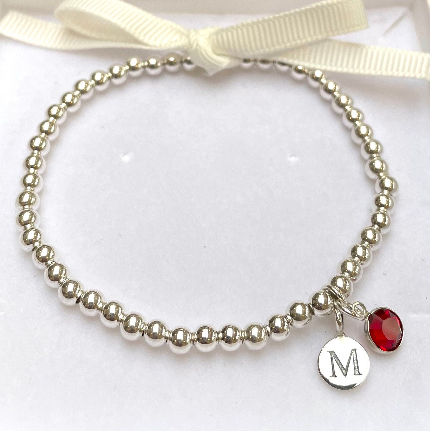Silver-plated elasticated bead bracelet with silver initial & birthstone charm